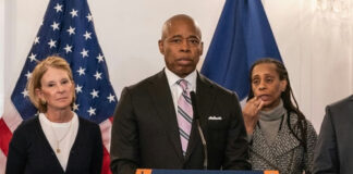 People standing at a podium with flags behind them.