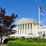 Supreme Court building with American flag and trees.
