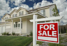 House with For Sale sign in front yard.
