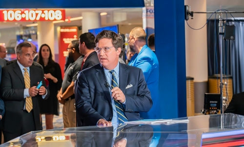 Man in suit speaking at a television studio.