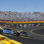Stock cars racing on a track with packed stands.