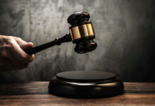 Hand holding judges gavel over sounding block.