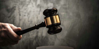 Hand holding judges gavel over sounding block.