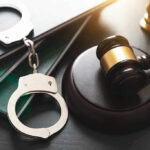 Handcuffs, gavel, and books on a table.
