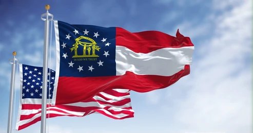 2144966627 Georgia state flag and U.S. flags waving on flagpoles against a blue sky