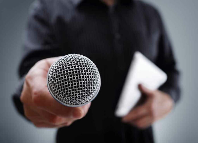 Person holding a microphone and a tablet.
