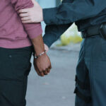Police officer arresting a person near a vehicle.