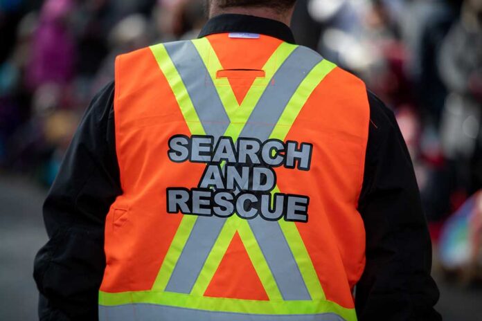 Search and rescue worker in an orange reflective vest seen from behind
