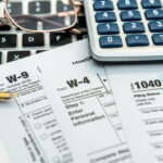 Tax forms with calculator, pen, and glasses on a keyboard