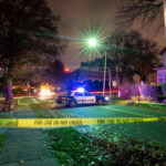 Police car with flashing lights at a crime scene surrounded by caution tape