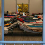 Interior view of a temporary shelter with rows of beds.