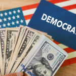 Hand holding money in front of Democrats sign.