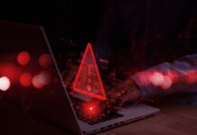 A person typing on a laptop with a red warning symbol overlay