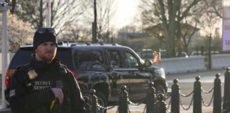 Secret Service agent standing near restricted area sign.
