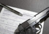 Form with gun and pen on table.