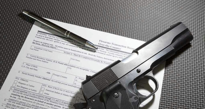 Form with gun and pen on table.