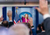 Manhattan Rents Soar — Board Slams Brakes Press secretary at podium, answering reporters questions, raised hands.