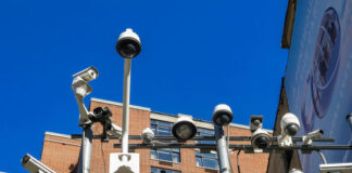 Array of security cameras mounted above a building facade under a clear blue sky