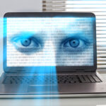 A laptop screen displaying a pair of blue eyes overlaid with binary code