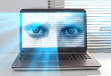 A laptop screen displaying a pair of blue eyes overlaid with binary code