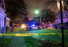 Police car with flashing lights at a crime scene surrounded by caution tape