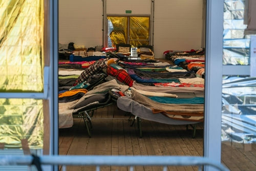 shutterstock_2139170565 Interior view of a temporary shelter with rows of beds.