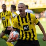Soccer player in yellow and black jersey celebrating with ball