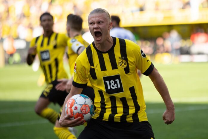 Soccer player in yellow and black jersey celebrating with ball