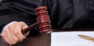 Judge striking a gavel on a wooden sound block.