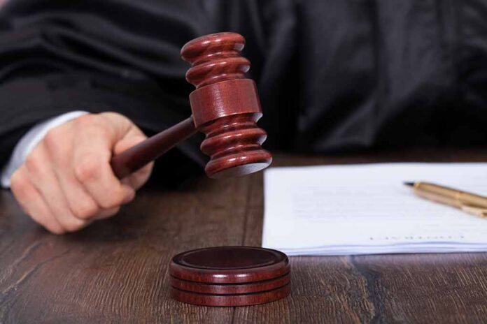 Judge striking a gavel on a wooden sound block.