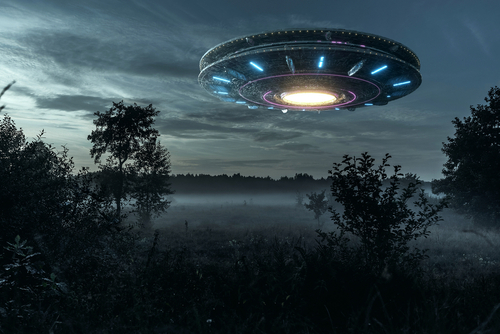 Flying saucer hovering over a misty forest clearing.