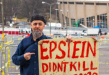 Man holding "Epstein didn't kill himself 2020" sign.