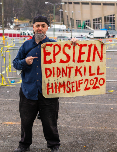 Man holding "Epstein didn't kill himself 2020" sign.