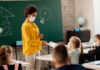 Teacher interacting with masked students in classroom.