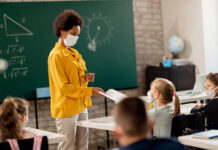 Teacher interacting with masked students in classroom.