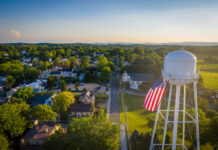 Water tower with American flag overlooking a small town.