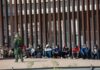 Border patrol agent with group of seated immigrants.