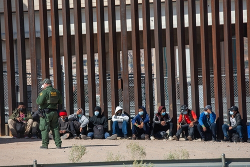 Border patrol agent with group of seated immigrants.