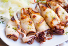 Grilled squid garnished with herbs and served with onions.