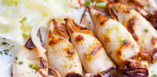 Grilled squid garnished with herbs and served with onions.