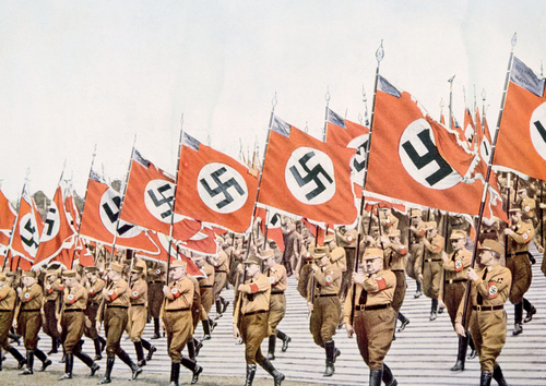 Nazi soldiers marching with swastika flags, World War II.