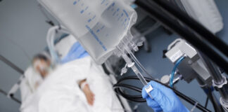 Patient in hospital bed with IV drip close-up.