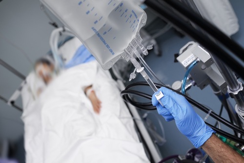 Patient in hospital bed with IV drip close-up.