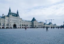 Large building with turrets, people walking in square.