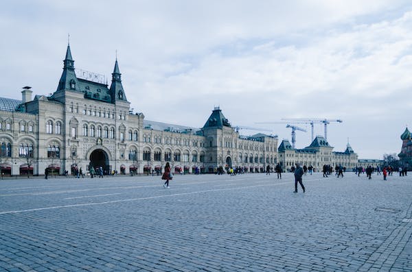 Large building with turrets, people walking in square.