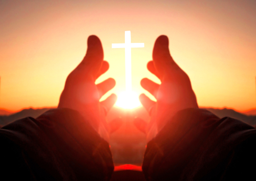 Hands reaching toward sun and cross at sunrise.