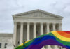 Supreme Court building with rainbow flag in foreground.